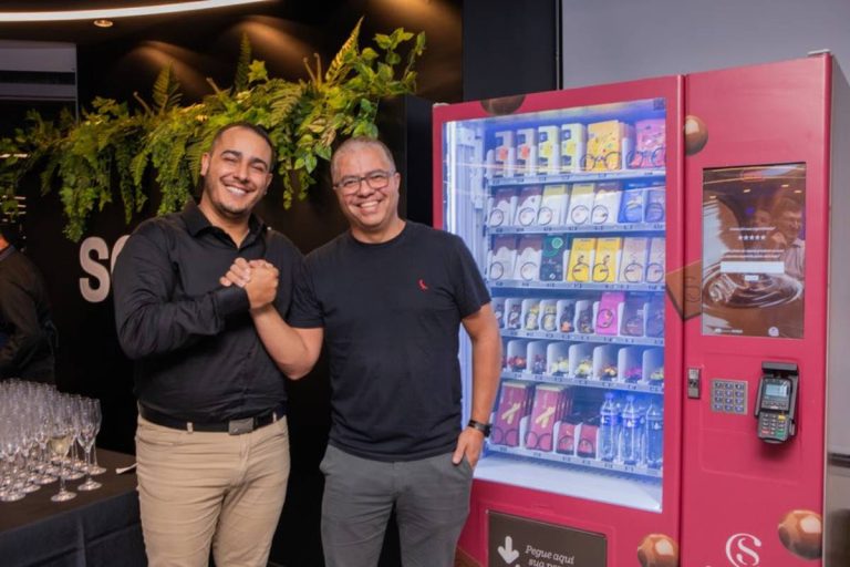 Dois franqueadores da Cacau Show ao lado da máquina de vendas Machine Show