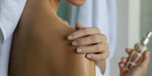 Mulher passando óleo corporal no ombro direito