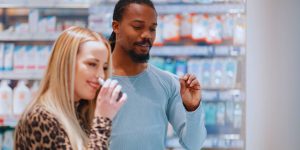 Mulher branca e homem negro provando perfumes em uma loja