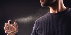 Homem de suéter passando perfume