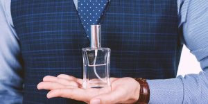homem segurando frasco de perfume na palma da mão