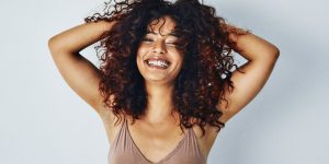 mulher jovem de cabelo cacheado sorrindo